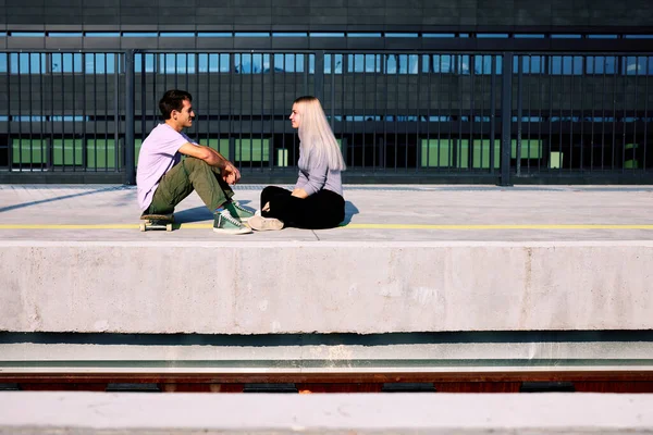 Mutlu genç bir çift tren istasyonunda oturmuş flört ediyor..