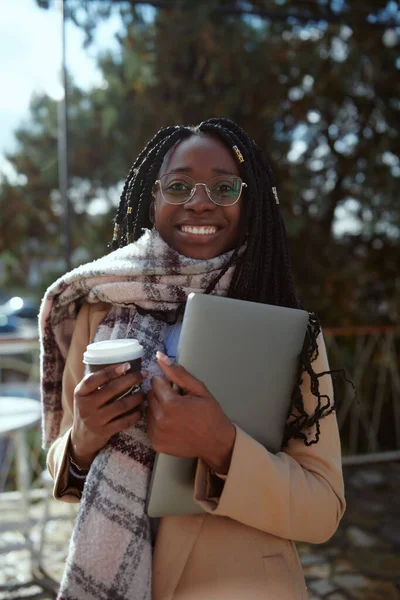 Szczęśliwa Młoda Afrykanka Stojąca Tarasie Kawiarni Kawą Wynos Laptopem Rękach — Zdjęcie stockowe