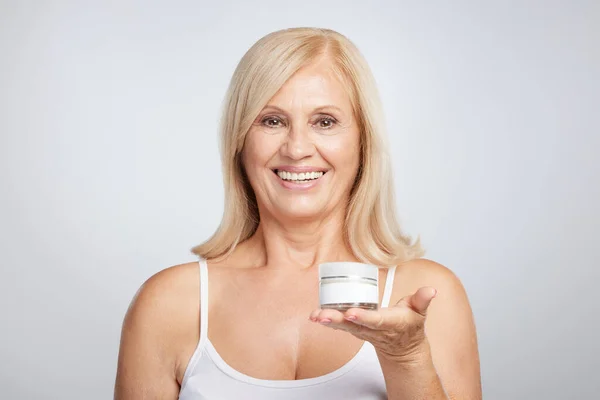 Happy Senior Blond Woman Holding Age Creme Hand Looking Camera — Stock Photo, Image