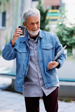 Mutlu bir son sınıf öğrencisi sokakta dizüstü bilgisayarını ve kahve fincanını tutuyor. Son sınıf öğrencisi bir konferansa gidiyor..