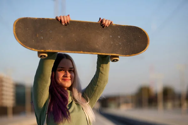 駅に立ってスケートボードを持っている都会の10代の少女 十代のスケーター女の子保持ザボード — ストック写真