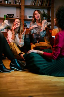 Mutlu çok kültürlü arkadaşlar evde oturup gülüyor, şarkı söylüyor ve karaoke gecesinde eğleniyorlar..