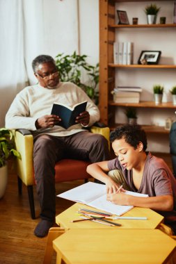Afrikalı bir dede evde oturur, kitap okur ve torununa arkadaşlık eder. Bir torun matematik ödevini yapıyor. Nesiller ve yaş farkı
