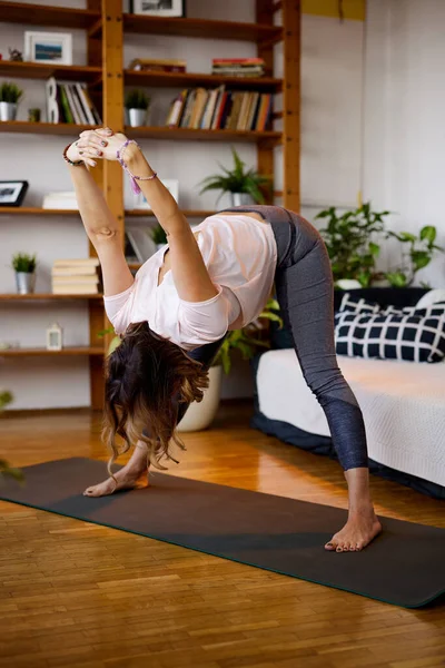 Una Mujer Flexible Está Parada Sobre Una Esterilla Yoga Practicando — Foto de Stock
