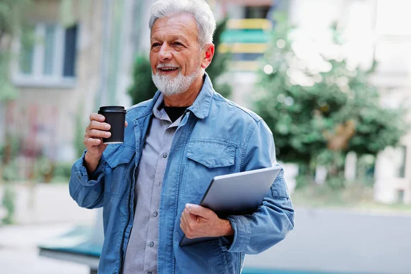 Mutlu bir son sınıf öğrencisi sokakta dizüstü bilgisayarını ve kahve fincanını tutuyor. Son sınıf öğrencisi bir konferansa gidiyor..