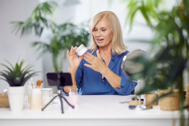 Yaşlı bir vlogger evde oturuyor ve yeni anti-yaş kreminden bahsediyor..