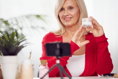 Yaşlı bir vlogger evde oturuyor ve yeni anti-yaş kreminden bahsediyor..