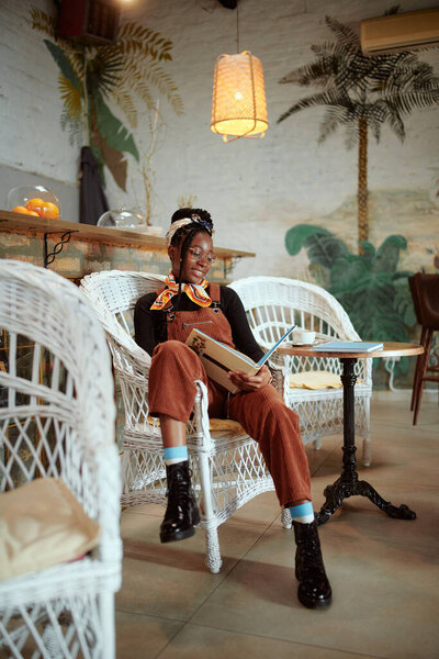 An African college girl is sitting casually at the cafeteria on campus and studying for the exam.
