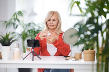 Yaşlı bir vlogger evde oturuyor ve yeni anti-yaş kreminden bahsediyor..