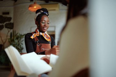 Genç bir Afrikalı kız öğrenci bir meslektaşıyla bir kafede oturuyor ve ders çalışıyor. Öğrenci değişim programı.