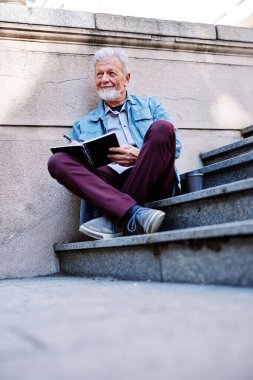 Üniversite binasının önündeki merdivenlerde oturan ve ödev yazan zeki bir son sınıf öğrencisi. Bir yeniden eğitim programının son sınıfları.