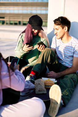 Mutlu genç arkadaşlar şehir dışında oturuyor ve telefonlarını sosyal medyada takılı kalmak için kullanıyorlar..