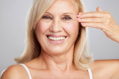 Anti-yaş kremi kullandıktan sonra gülümseyen son sınıf kadınının yüzü.