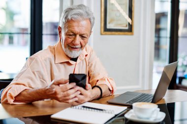 Bir son sınıf öğrencisi kafede oturuyor ve öğrenim sırasında telefonu kullanıyor..