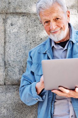 Mutlu bir son sınıf öğrencisi duvara dayanıyor ve dizüstü bilgisayarda yazıyor..