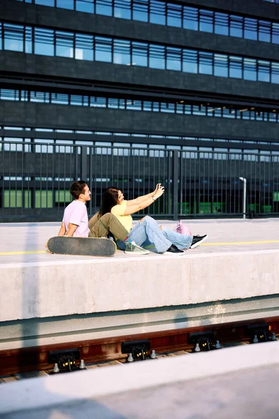 Teenageři Sedí Vlakovém Nádraží Městském Exteriéru Dívají Fotografie Digitálním Fotoaparátu — Stock fotografie