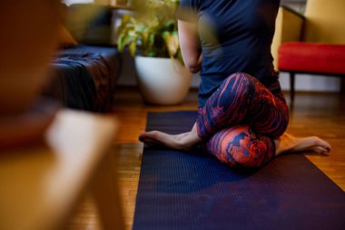 Esnek bir kadın evde yoga minderinde oturuyor. Ayakkabı bağcığı yoga duruşu ve meditasyon..