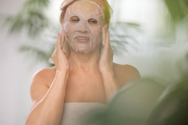 Senior Woman Putting Beauty Face Mask Her Face While Sitting — Stock Photo, Image