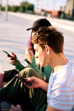 Sosyal medyaya bağımlı iki genç şehir dışında oturuyor ve telefon kullanıyorlar..