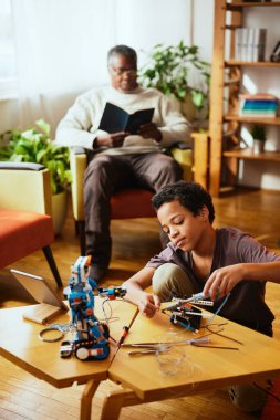 Büyükbaba kitap okurken evde robot yapan bir torun..