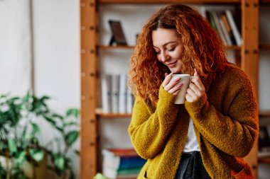 Zencefilli bir kızın portresi sabah kahvesiyle bir kupa tutuyor ve cümlesini kuruyor..