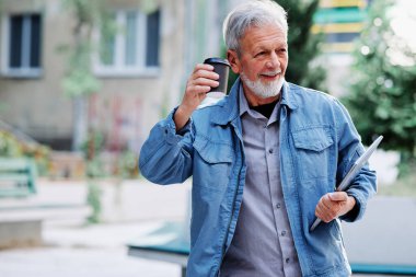 Mutlu bir son sınıf öğrencisi sokakta dizüstü bilgisayarını ve kahve fincanını tutuyor. Son sınıf öğrencisi bir konferansa gidiyor..