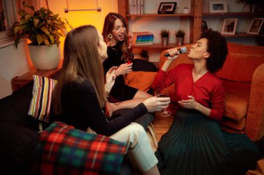 Afrikalı bir kadın evde oturuyor, karaoke partisinde şarkı söylüyor..