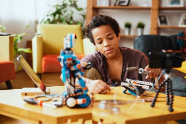 Eğitimli küçük bir çocuk kendini bir video bloğu için kaydediyor ve bir robot yapıyor. Elektronik ve yapay zeka eğitimi.