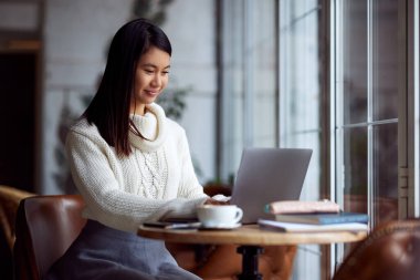 Asyalı bir kız öğrenci, kafede dizüstü bilgisayarda ders verdikten sonra değişime uğradı..