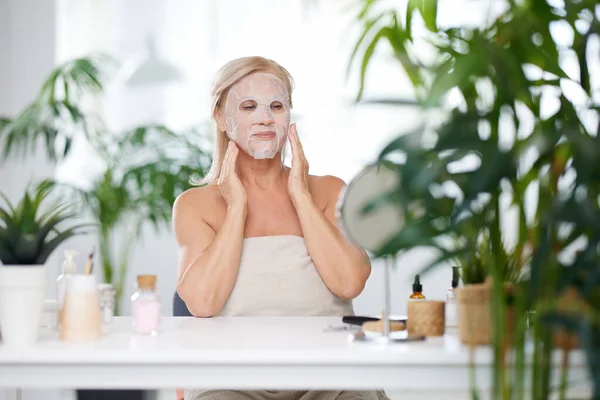 Starsza Kobieta Zakładająca Maskę Twarz Siedząc Domu Owinięta Ręcznik Starsza — Zdjęcie stockowe