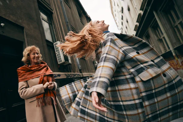 一个嬉闹的孙女在街上为她的祖母打转跳舞 — 图库照片