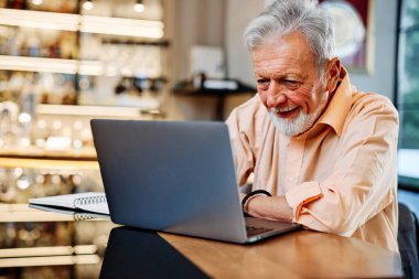 Bir son sınıf öğrencisi kafeteryada oturuyor ve internetteki derslerini dikkatle izliyor..