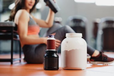 Sporcu bir kadınla spor salonundaki takviyelere ve protein gücüne odaklan..