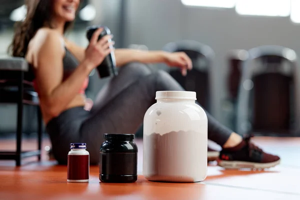 Foco Seletivo Proteína Frascos Multivitamínicos Chão Ginásio Com Uma Mulher — Fotografia de Stock