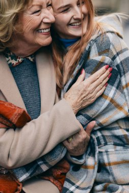 Büyükanne ve ergen torun soğuk havada sokakta yürürken birbirlerine sarılıyorlar..