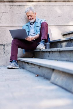 Üst sınıflardan biri, parktaki merdivenlerde otururken bilgisayardaki e-postalarını kontrol ediyor..