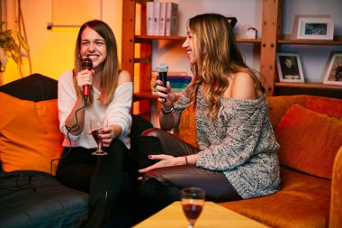 İki güzel genç kadın bir ev partisinde karaoke yapıyor..