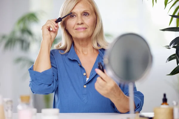 Une Femme Âgée Souriante Assise Son Coin Beauté Mettant Mascara — Photo