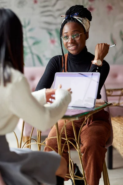 İki çok kültürlü kız öğrenci, kafeteryada kahve içerken dizüstü bilgisayarlarında proje yapıyor..