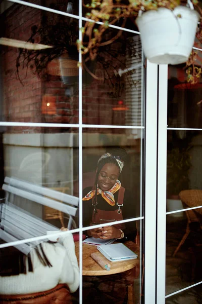 Widok Przez Okno Młodą Afrykańską Hipsterkę Studiującą Kafejce Internetowej — Zdjęcie stockowe