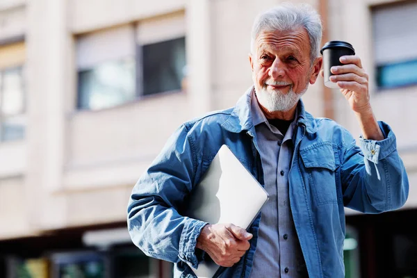 Dizüstü bilgisayarı ve kahvesi olan kıdemli bir girişimci bir müşteriyle buluşmaya gitmek için acele ediyor..