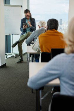 Genç bir eğitimci sınıftaki son sınıf öğrencilerinden oluşan çok kültürlü bir gruba ders veriyor..