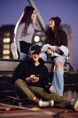 Genç arkadaşlar gecenin bir yarısı çatıdaki partide bira şişeleriyle takılıyorlar..