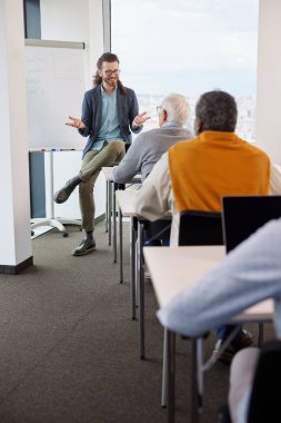 Genç bir eğitimci sınıftaki son sınıf öğrencilerinden oluşan çok kültürlü bir gruba ders veriyor..