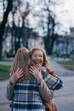 Mutlu bir büyükanne ve torun dışarıda sarılır..