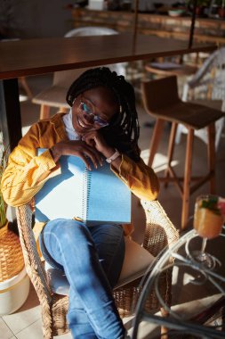 Çok kültürlü mutlu bir kız bir kafede oturur ve okumaya ara verir..