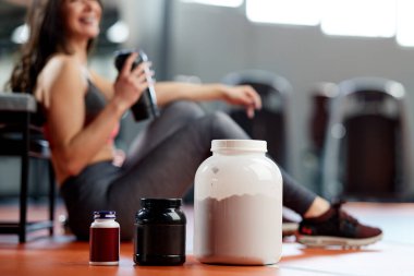 Sporcu bir kadınla spor salonundaki takviyelere ve protein gücüne odaklan..