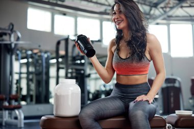 Genç aktif bir kadın spor salonuna gidip protein içeceği içiyor..