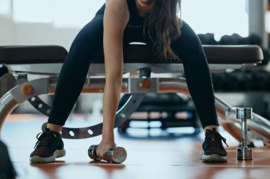 A female bodybuilder doing exercises with dumbbell for biceps.