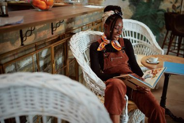 Çok kültürlü bir kız kahve dükkanında ansiklopedi okuyor ve eğleniyor..